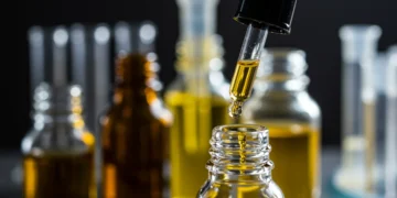 Frasco de óleo de cannabis sendo gotejado, simbolizando tratamento para dor crônica.